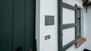 Une entrée d’immeuble avec une porte verte, une enseigne indiquant « Dunewin 9 » et une boîte aux lettres.