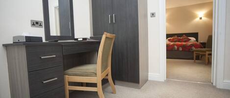 A bedroom with a bed, a bedside table, and a chair.