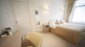 A hotel room with a bed, bedside table, chair, and a window with curtains. - The White Swan Hotel (Halifax)