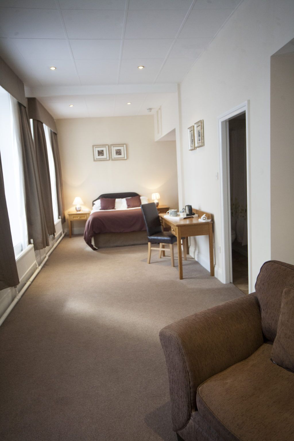 Una habitación de hotel con cama, escritorio, silla y sofá.