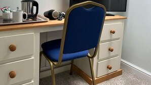 A small, neatly organized room with a desk, chair, and a large TV. - The White Swan Hotel (Halifax)