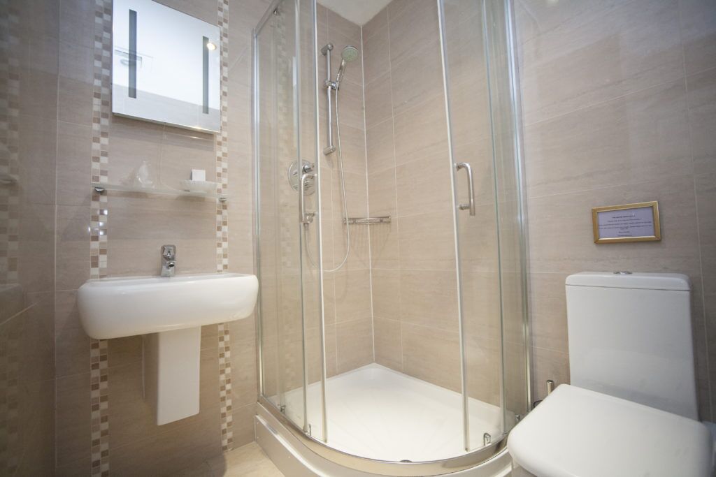 Une salle de bain avec une douche à parois de verre, un lavabo blanc et des toilettes.