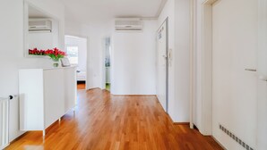 A hallway with wooden flooring, white walls, and a white cabinet with red flowers. - Cherry City Stay Apartment With Parking (Zagreb)