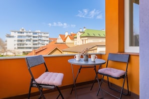 A balcony with two chairs and a small table, overlooking a residential area with various buildings. - Cherry City Stay Apartment With Parking (Zagreb)