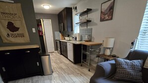 A modern kitchen with dark cabinets, a central island, and a dining area with a table and chairs.