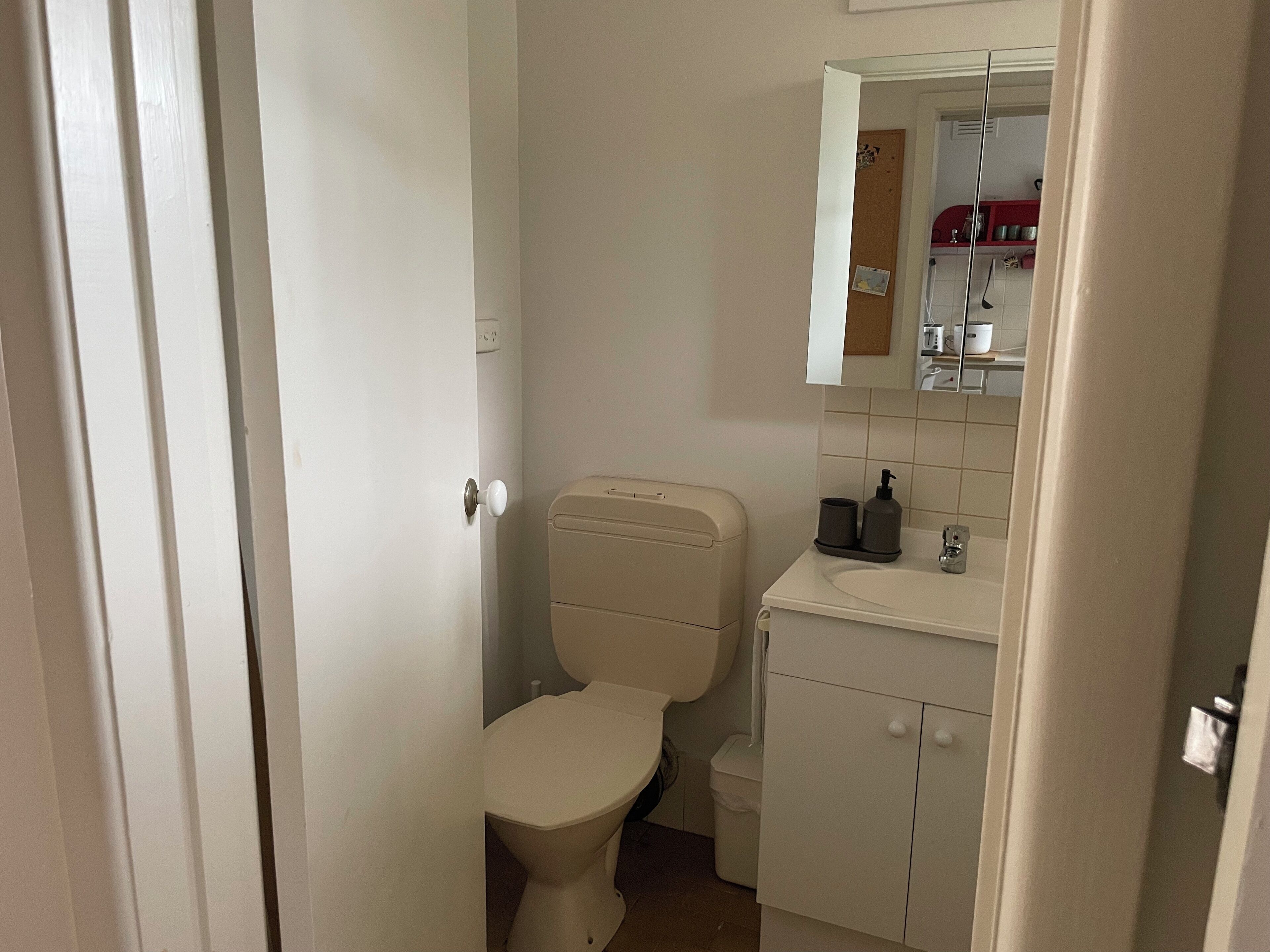 Un baño pequeño y limpio con inodoro, lavabo y espejo.