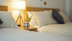 Un lit bien fait, avec une lampe, une petite plante et une table de chevet sur laquelle se trouve un bol.