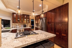 A modern kitchen with a large island, stainless steel appliances, and dark wooden cabinets. - Ocean/Catalina View Home fronting Monarch Links Golf Course walk to Ritz Cove! (Dana Point)
