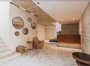 A modern interior with a marble floor, a wooden reception desk, and a staircase.