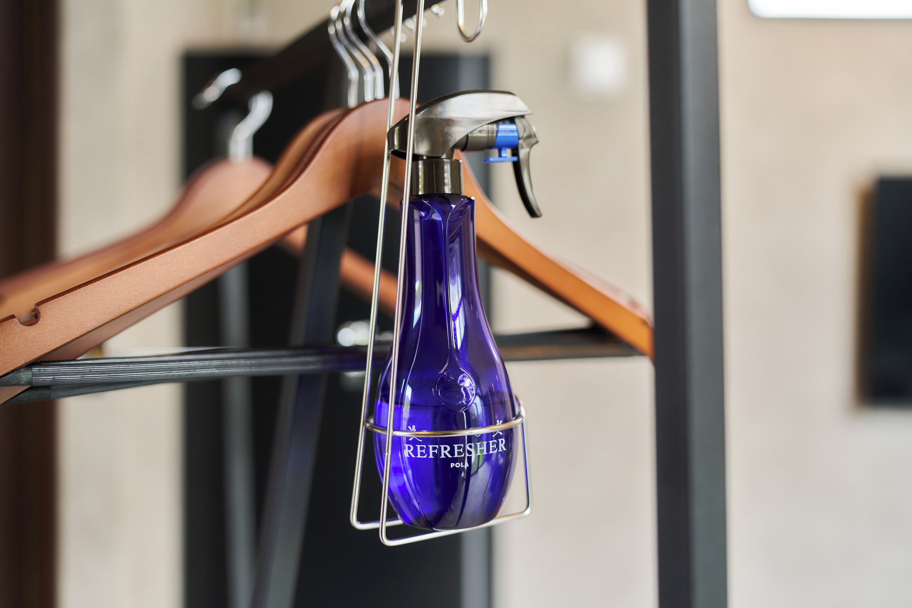 Eine blaue Flasche mit dem Aufdruck 'REFRESHER POLISH', die an einem Metallgestell hängt.