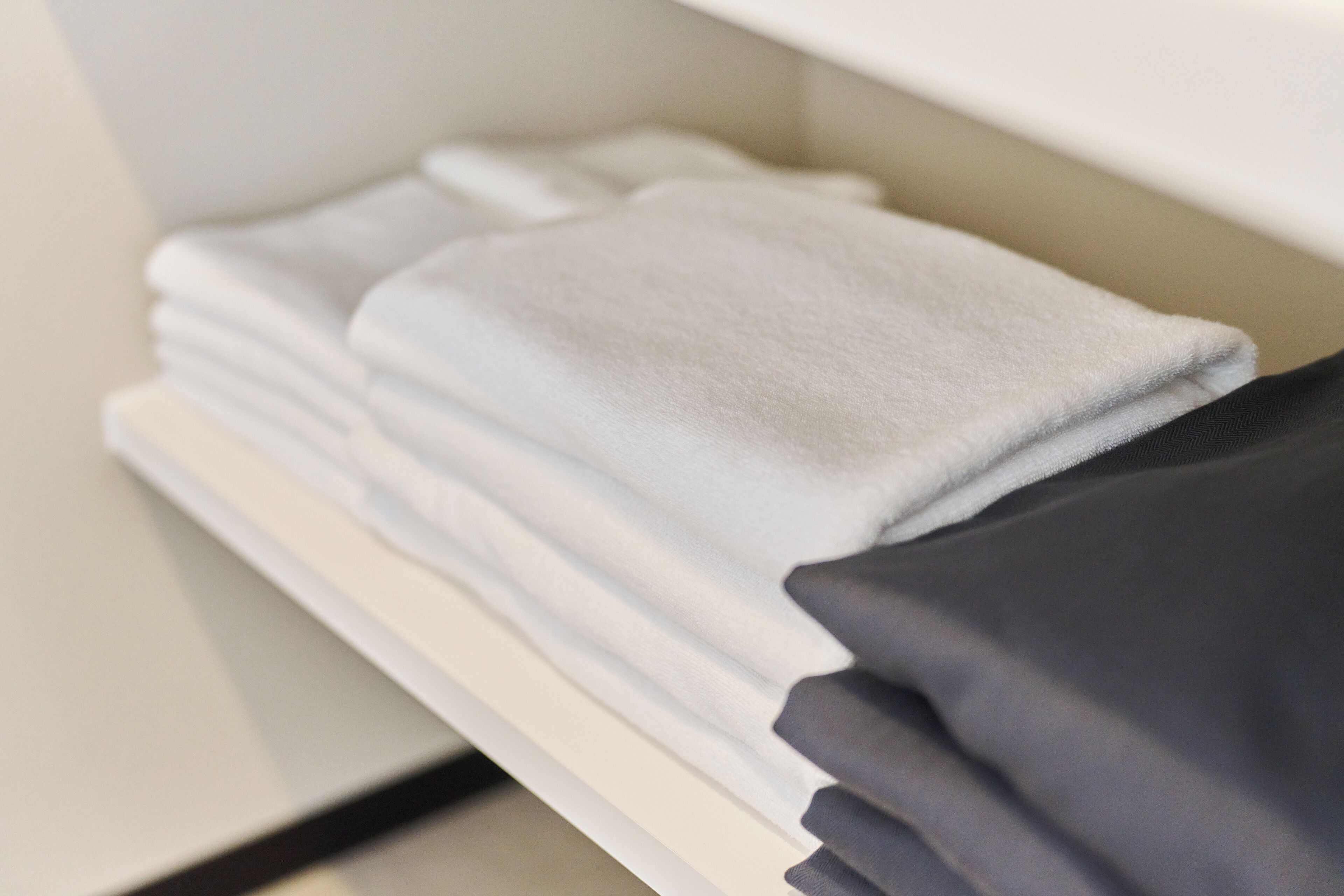 Une pile de serviettes soigneusement pliées, posée sur une étagère blanche.