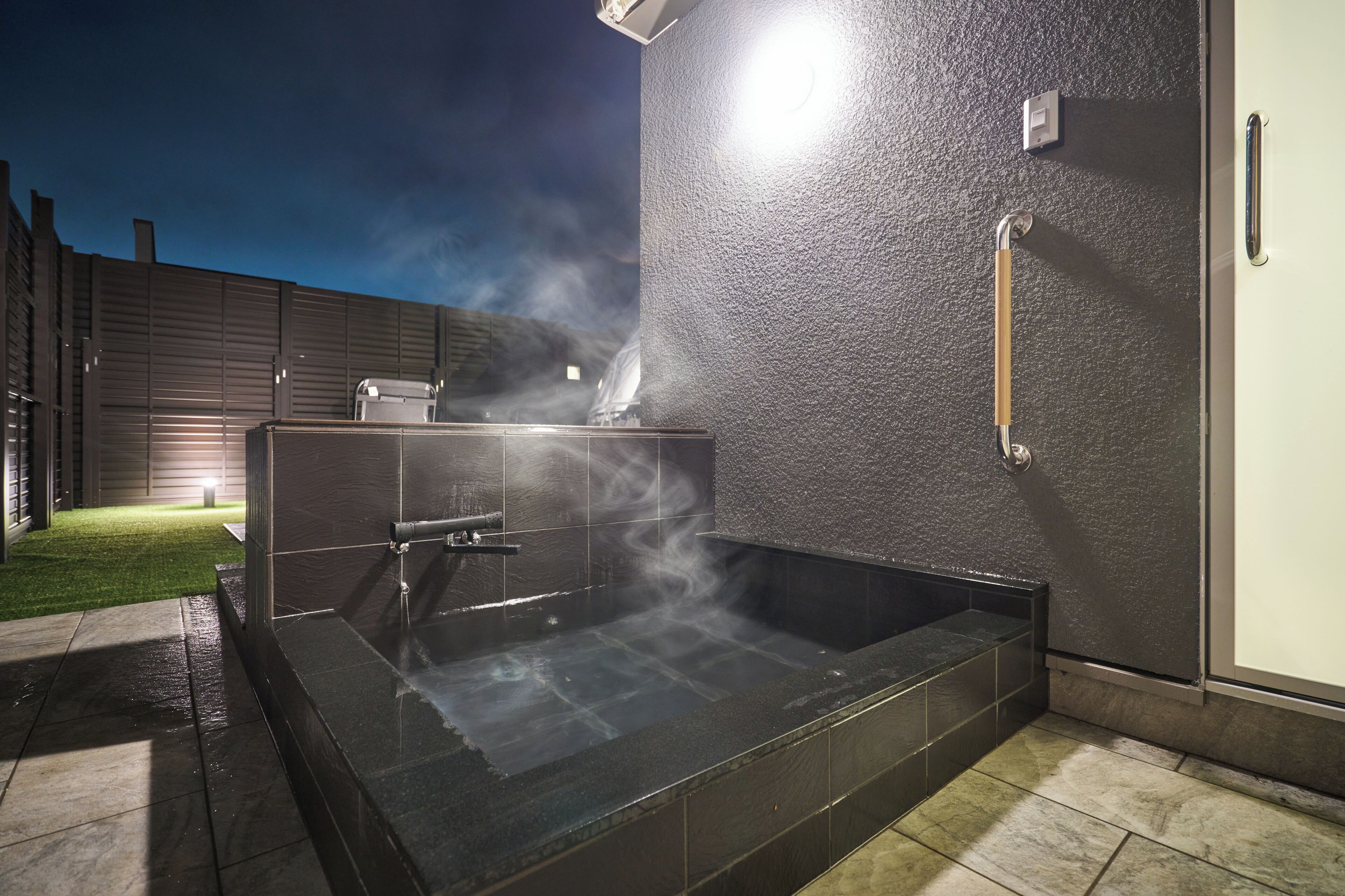 A spa area with a hot tub, a shower, and a towel rack.