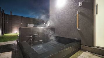A spa area with a hot tub, a shower, and a towel rack.