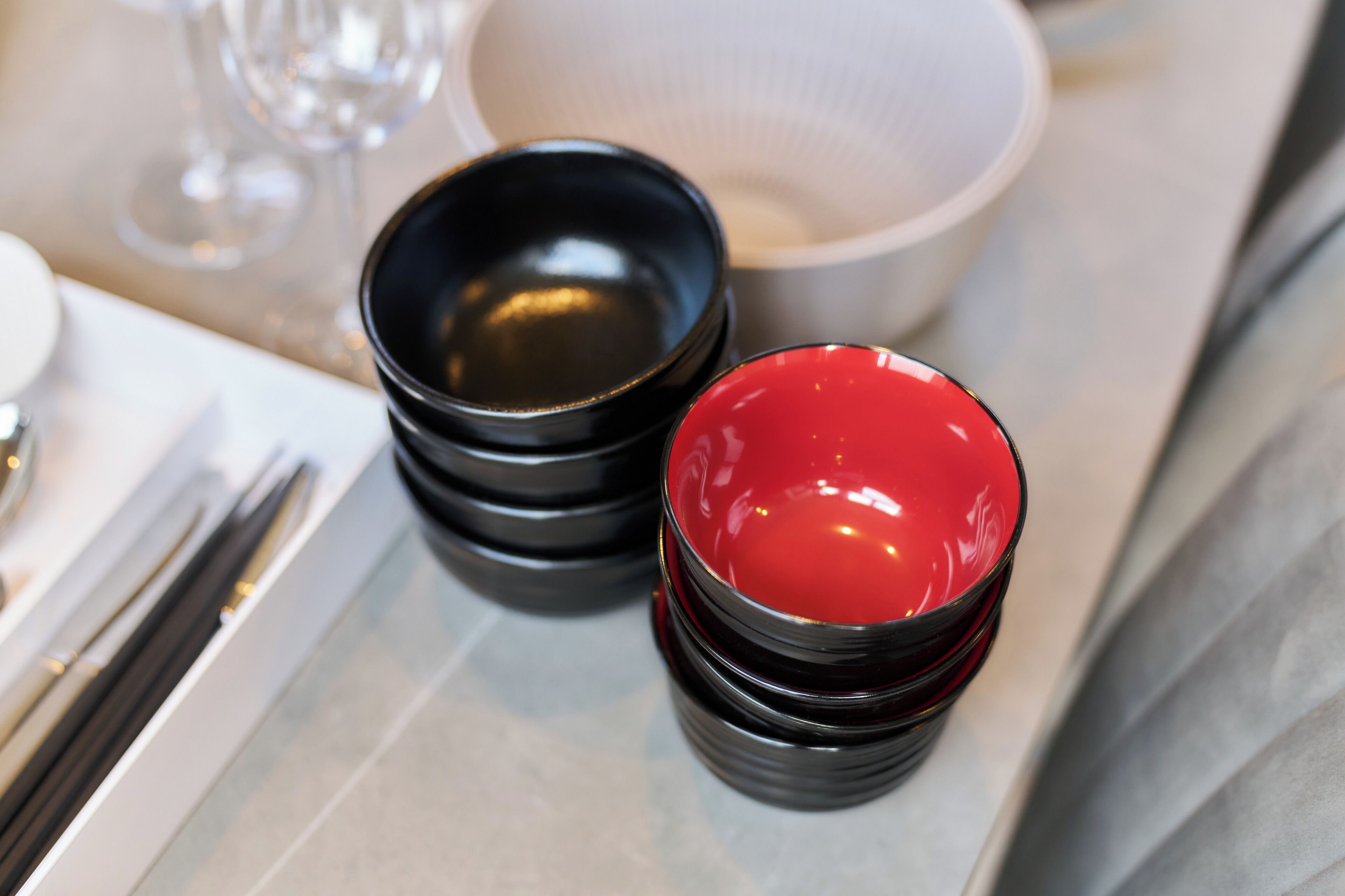 A table setting with black and red bowls, a white bowl, and a glass.