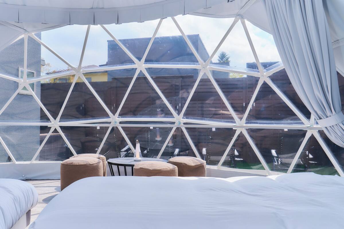 Ein Zimmer mit großem Fenster, einem Bett und zwei Stühlen.