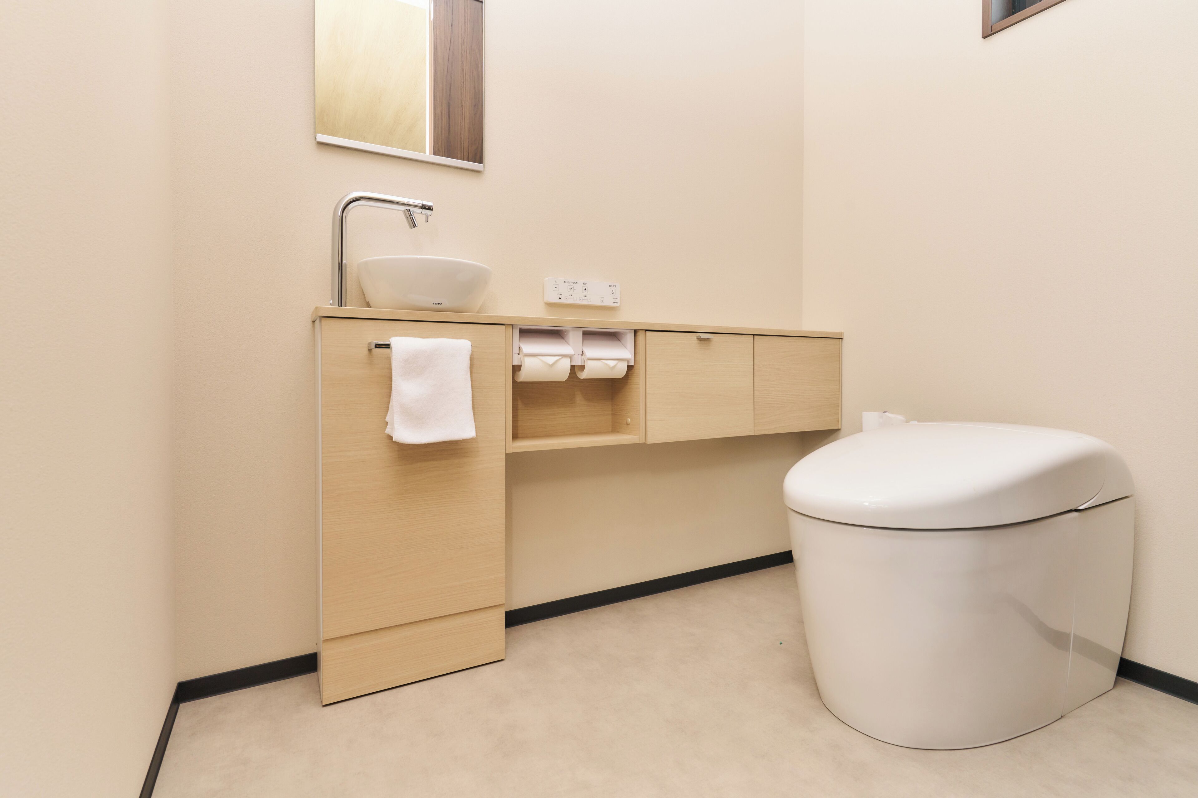Un baño moderno con un lavamanos, espejo y retrete blancos.