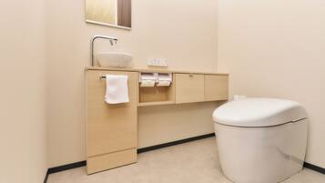 Un baño moderno con un lavamanos, espejo y retrete blancos.