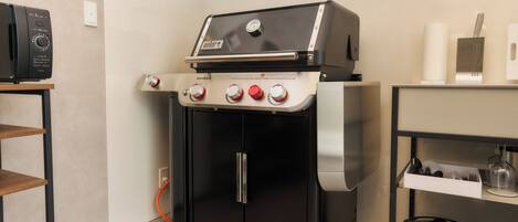 A compact kitchen with a built-in grill, a coffee machine, and a dish rack.
