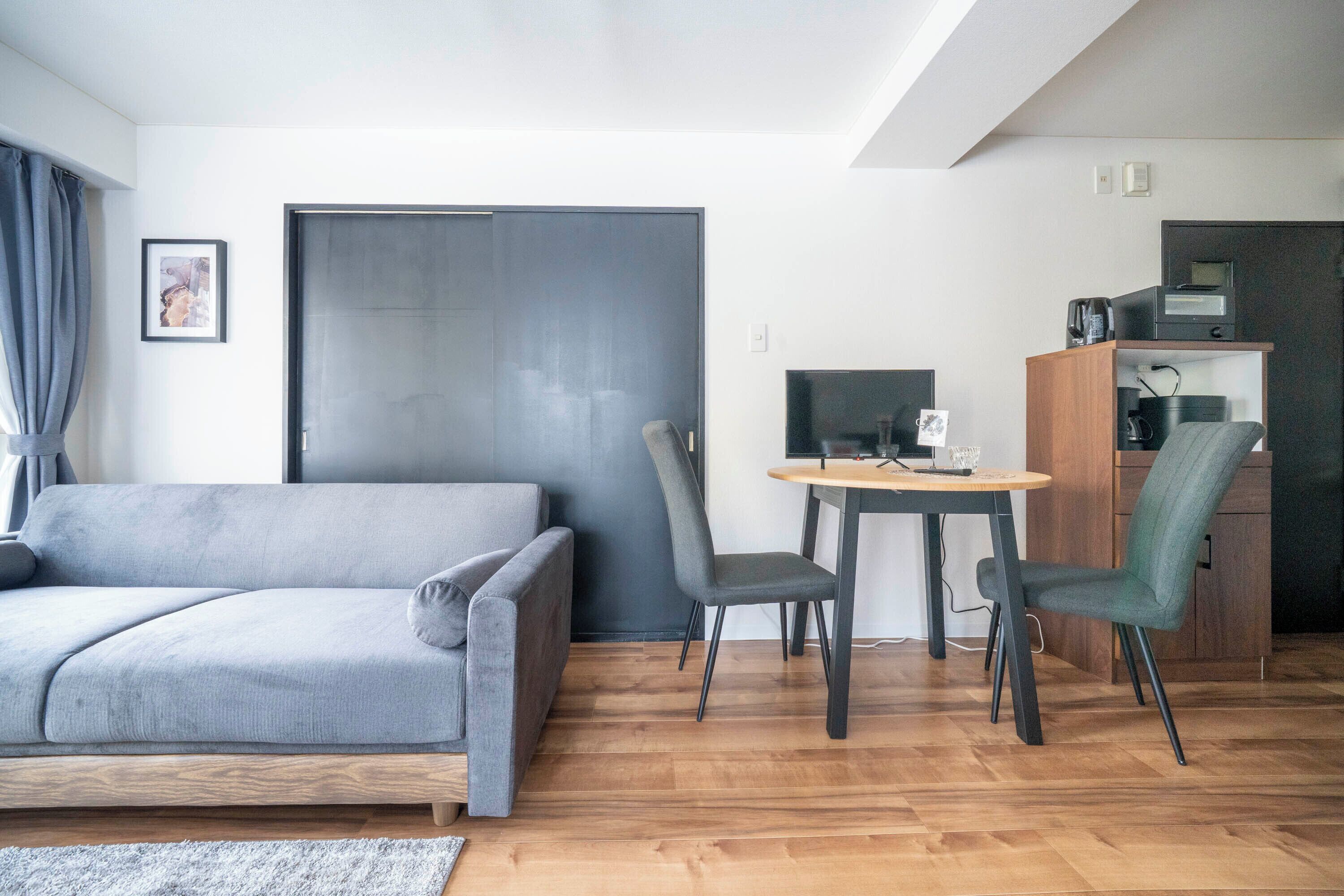 A modern living room with a grey sofa, a wooden coffee table, and a TV.
