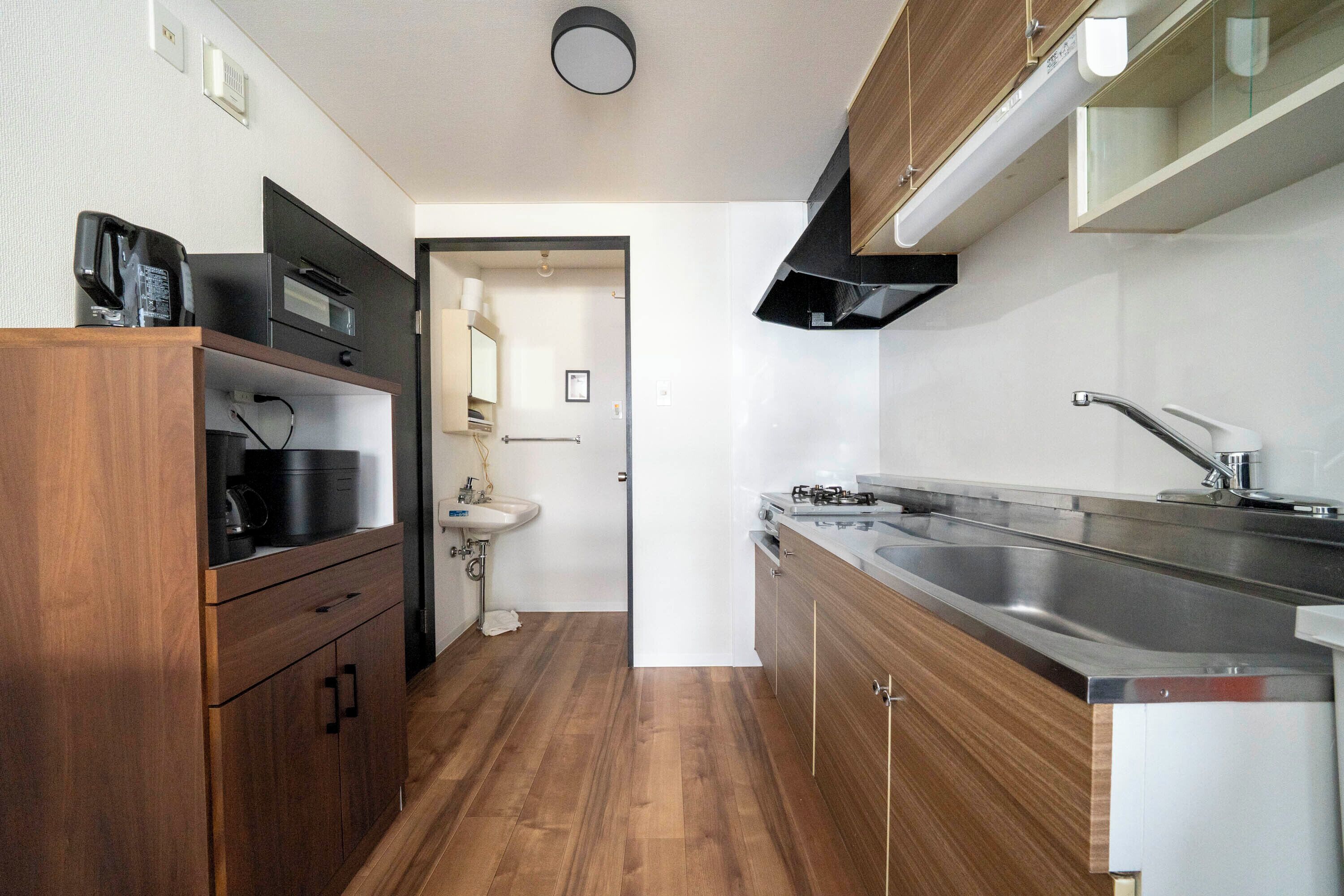 Une cuisine de taille réduite, avec des meubles de rangement en bois, un évier, une cuisinière et un four à micro-ondes.