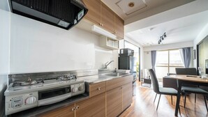 Een moderne keuken met een ingebouwde kookplaat, een magnetron en een spoelbak. Er is een eethoek met een tafel en stoelen.