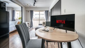 Een moderne hotelkamer met een bed, een televisie, een eettafel en een bank.