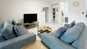 Ett modernt vardagsrum med två grå soffor, ett soffbord i trä och en tv med platt skärm.