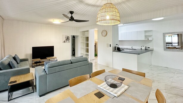 Ett modernt vardagsrum med en soffa, en tv och en matplats med bord och stolar.