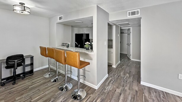 Una cocina moderna con barra, suelo de madera y decoración en tonos blancos.