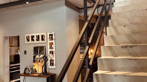 A staircase with a metal handrail leading to a loft area with exposed brick walls and a mezzanine level. - The Citadel @ Tether&Tease, Extraordinary BDSM Location in Cape Town (Cape Town)