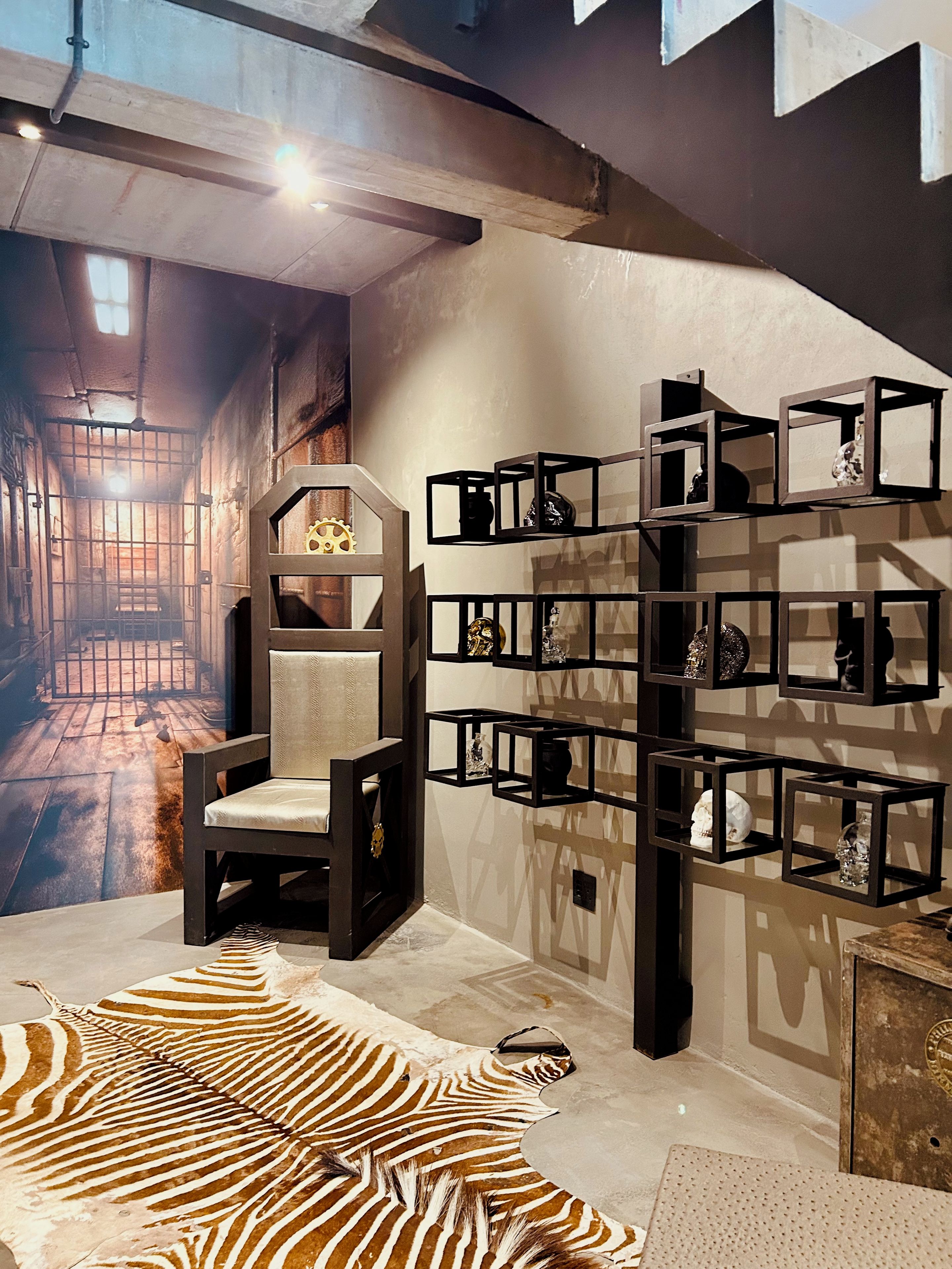 A room with a zebra-patterned rug, a chair, and a wall-mounted shelf with decorative items.