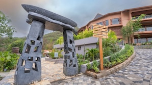 A stone archway with directional signs for amenities like a swimming pool, party deck, restaurant, and washrooms.