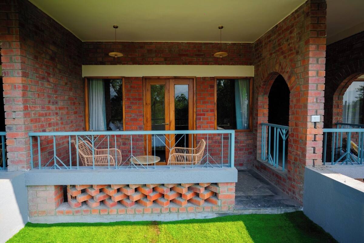 A brick building with a balcony, two wicker chairs, and a small table.