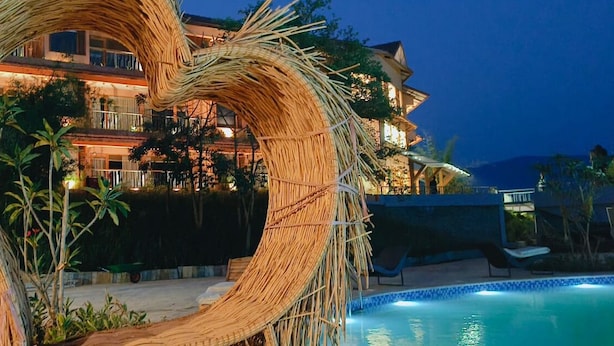 A resort with a large pool, a thatched structure, and a multi-story building with balconies.