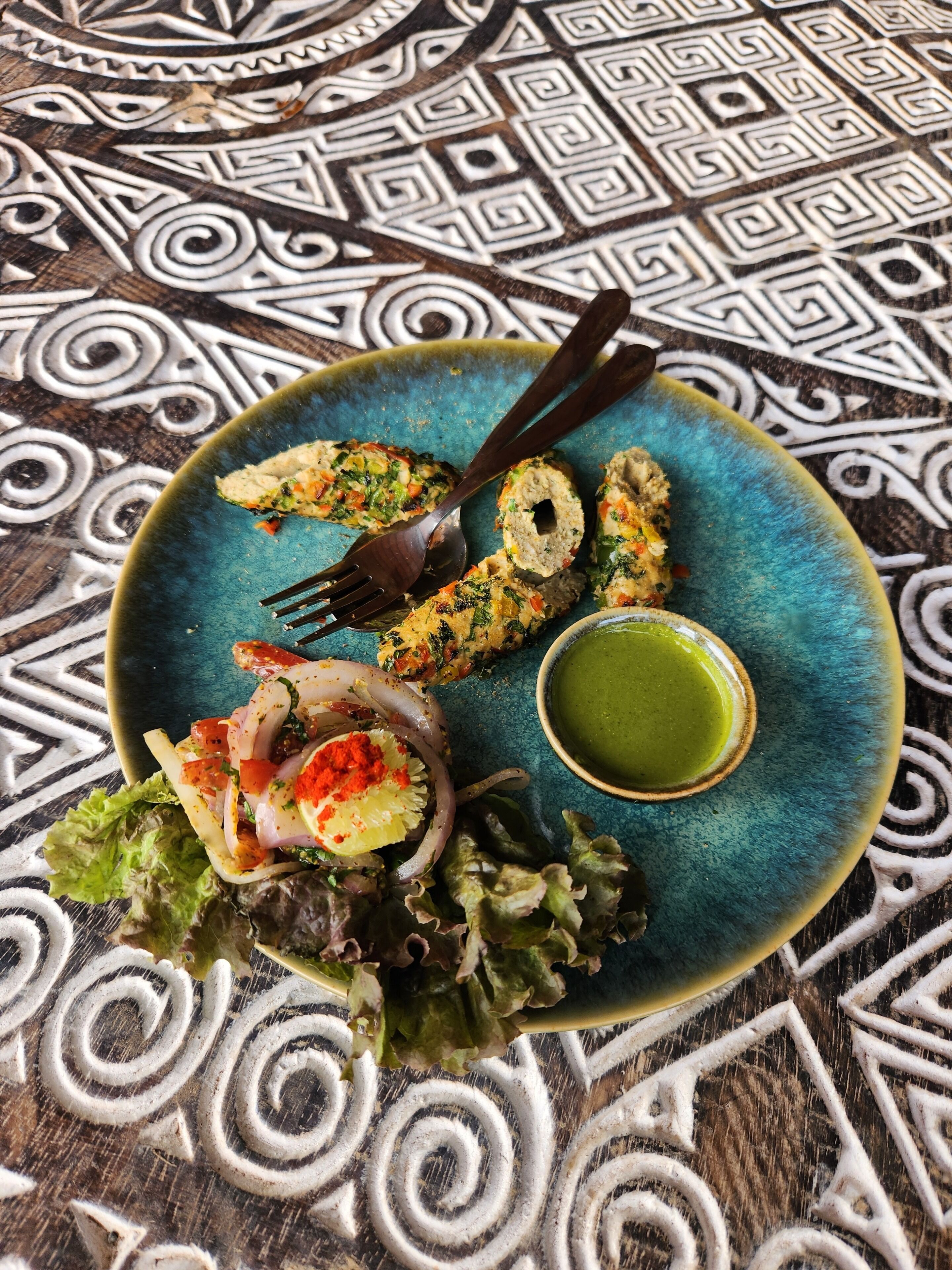 A plate with food and a fork on a patterned tablecloth.