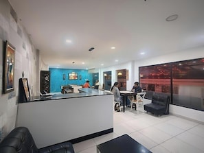 A reception area with a counter, seating, and a large window. - Veu Munnar Retreat (Devikolam)