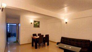 A modern living room with a dining area, a sofa, and a coffee table. - Veu Munnar Retreat (Devikolam)
