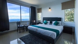 Quarto de hotel moderno com uma cama grande, uma escrivaninha e vista do céu.