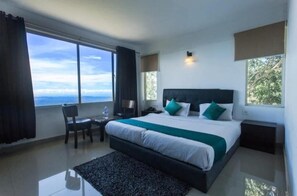 A modern hotel room with a large bed, a desk, and a view of the sky. - Veu Munnar Retreat (Devikolam)