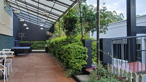 A covered outdoor area with a ping pong table, chairs, and a wall of greenery. - Veu Munnar Retreat (Devikolam)