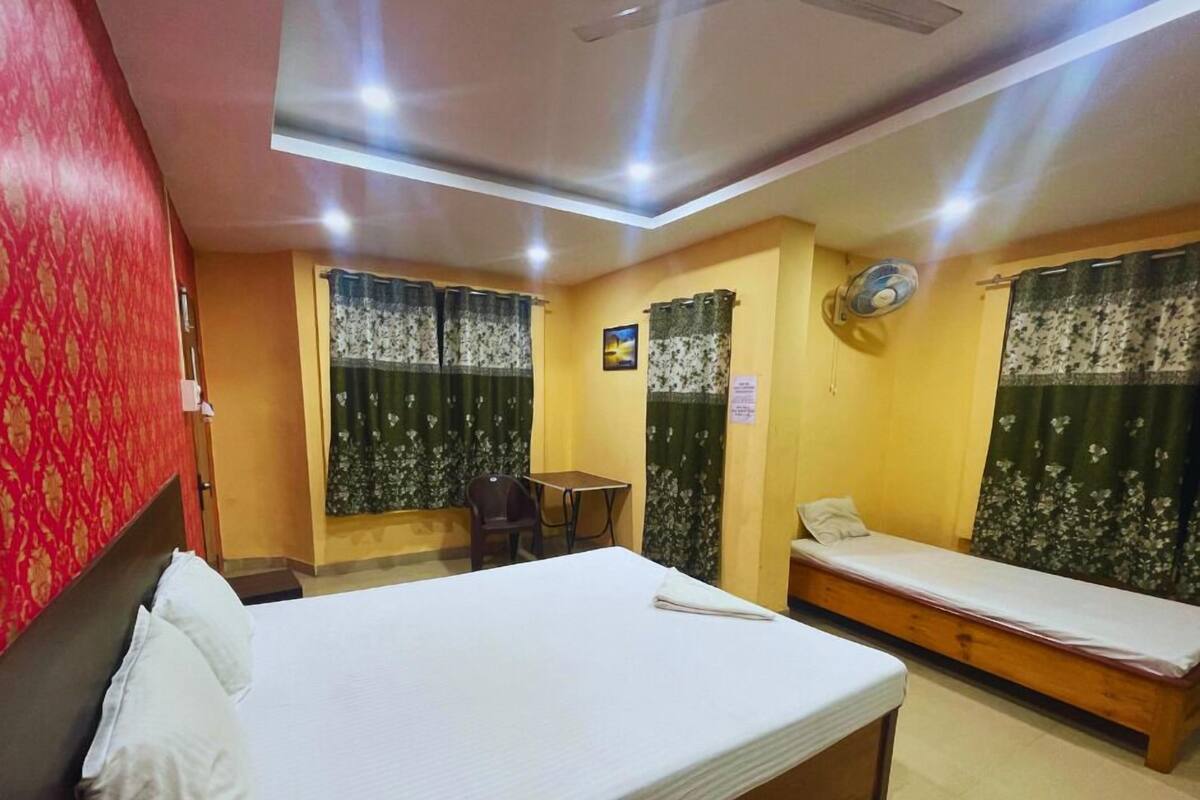 A hotel room with a large bed, a smaller bed, a desk, and a chair.