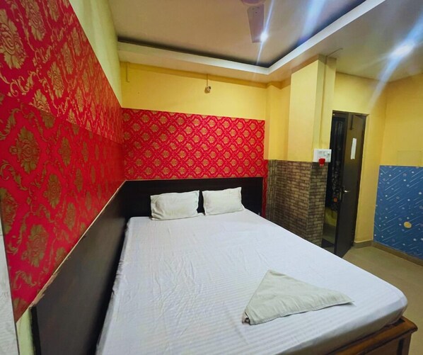 A hotel room with a bed, a wardrobe, and a red patterned wall.