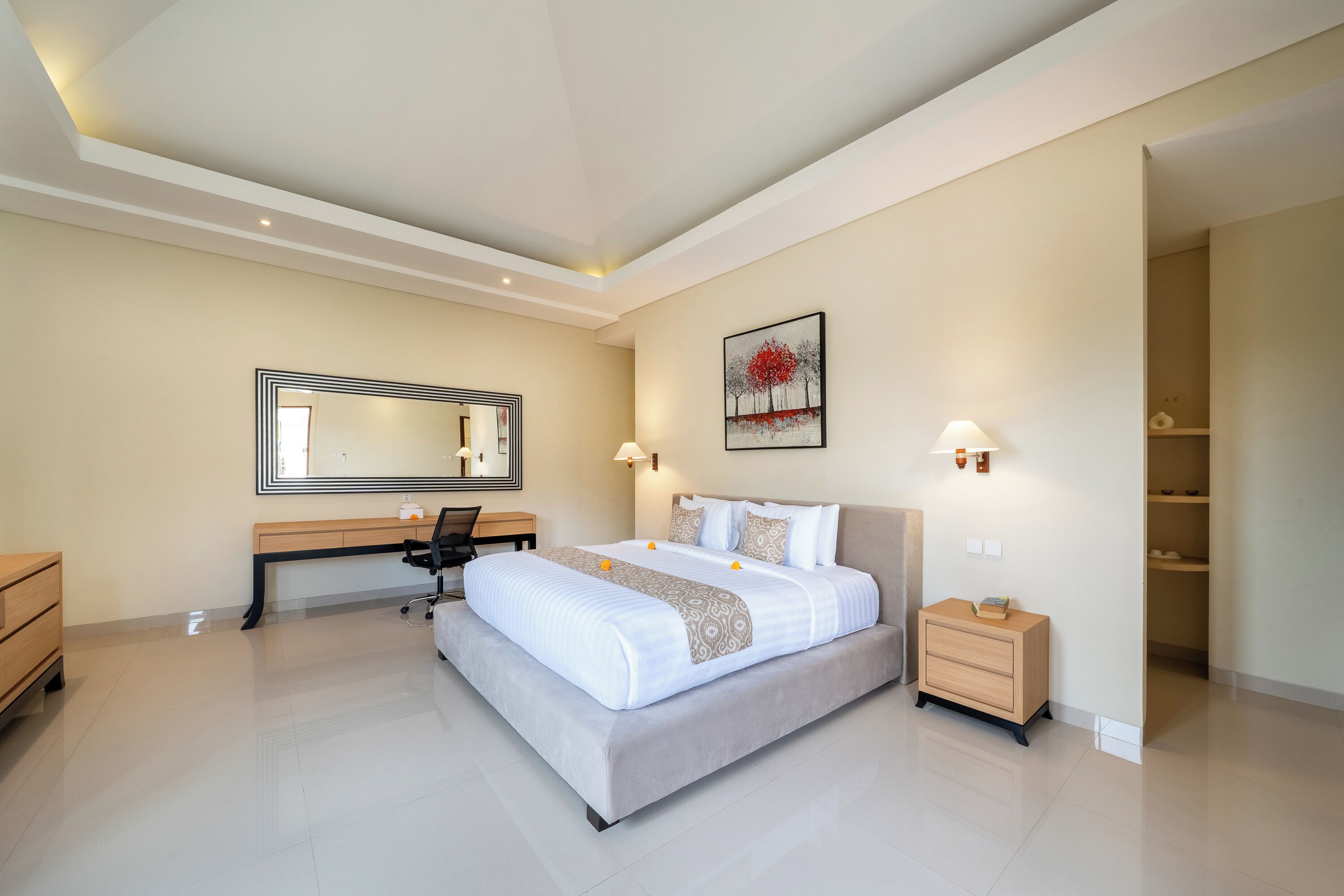 A modern hotel room with a large bed, a desk, and a wardrobe.