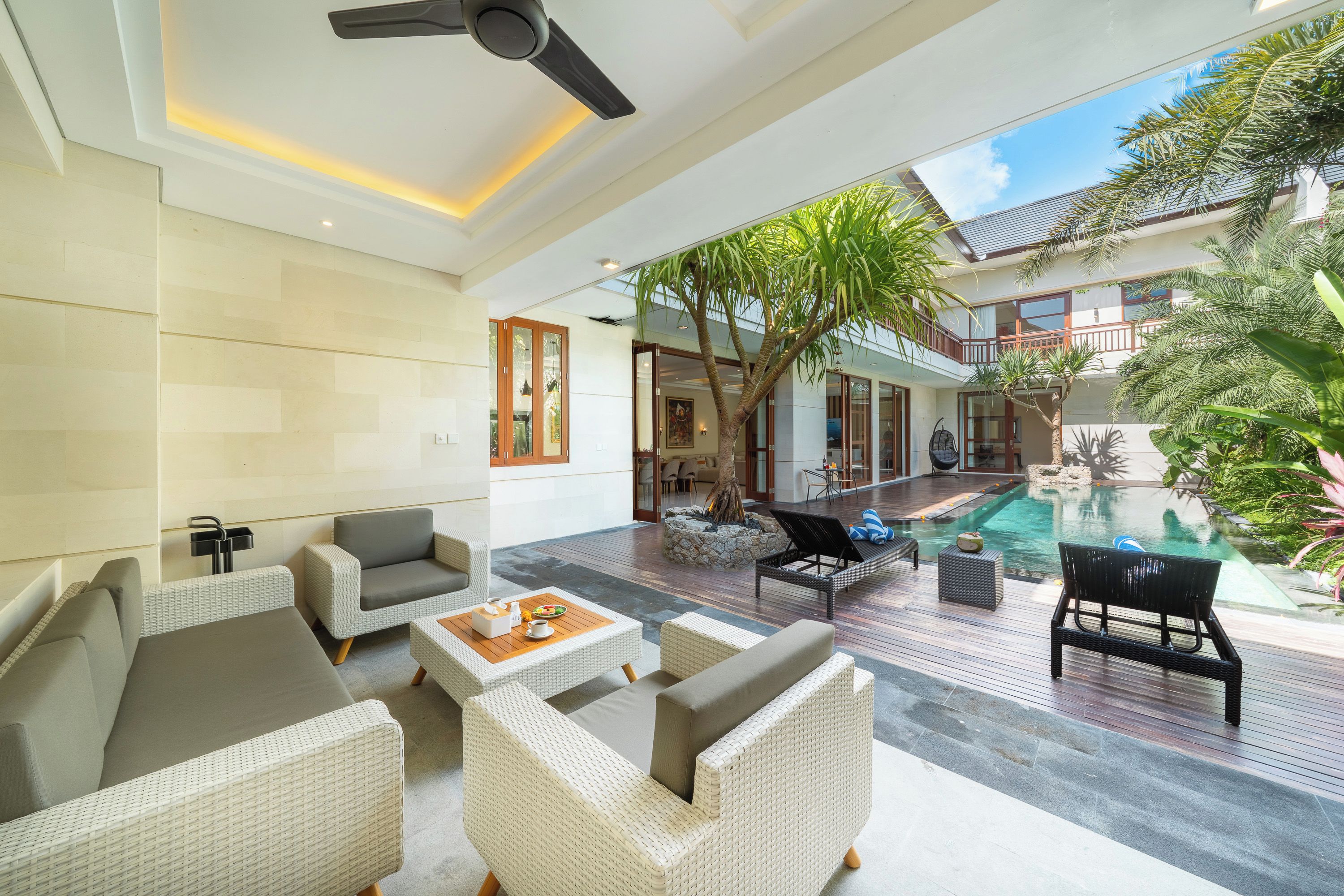 A spacious indoor area with a pool, outdoor seating, and a ceiling fan.