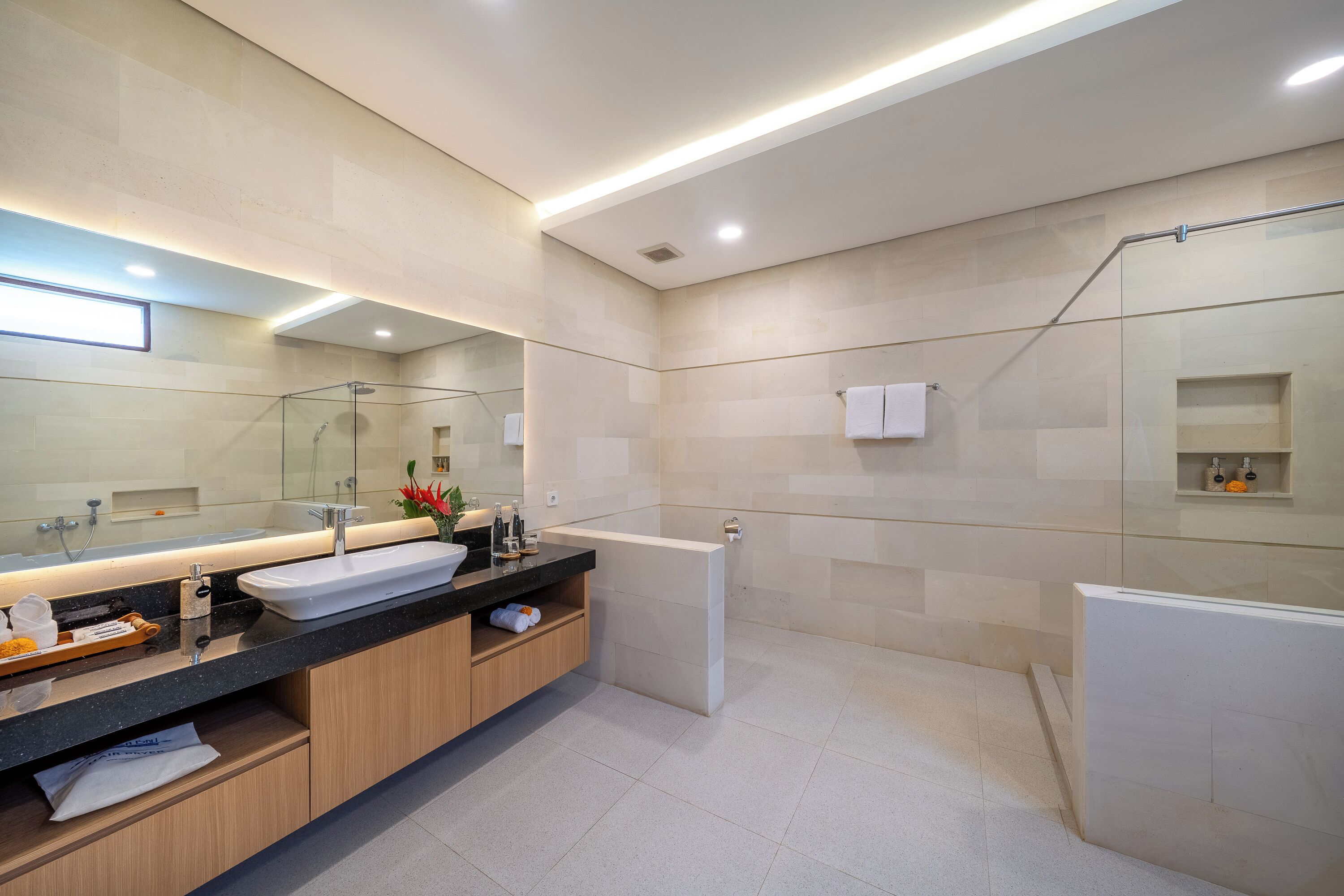 Ein modernes Badezimmer mit einem großen Spiegel, einem Waschbecken und einer Badewanne.