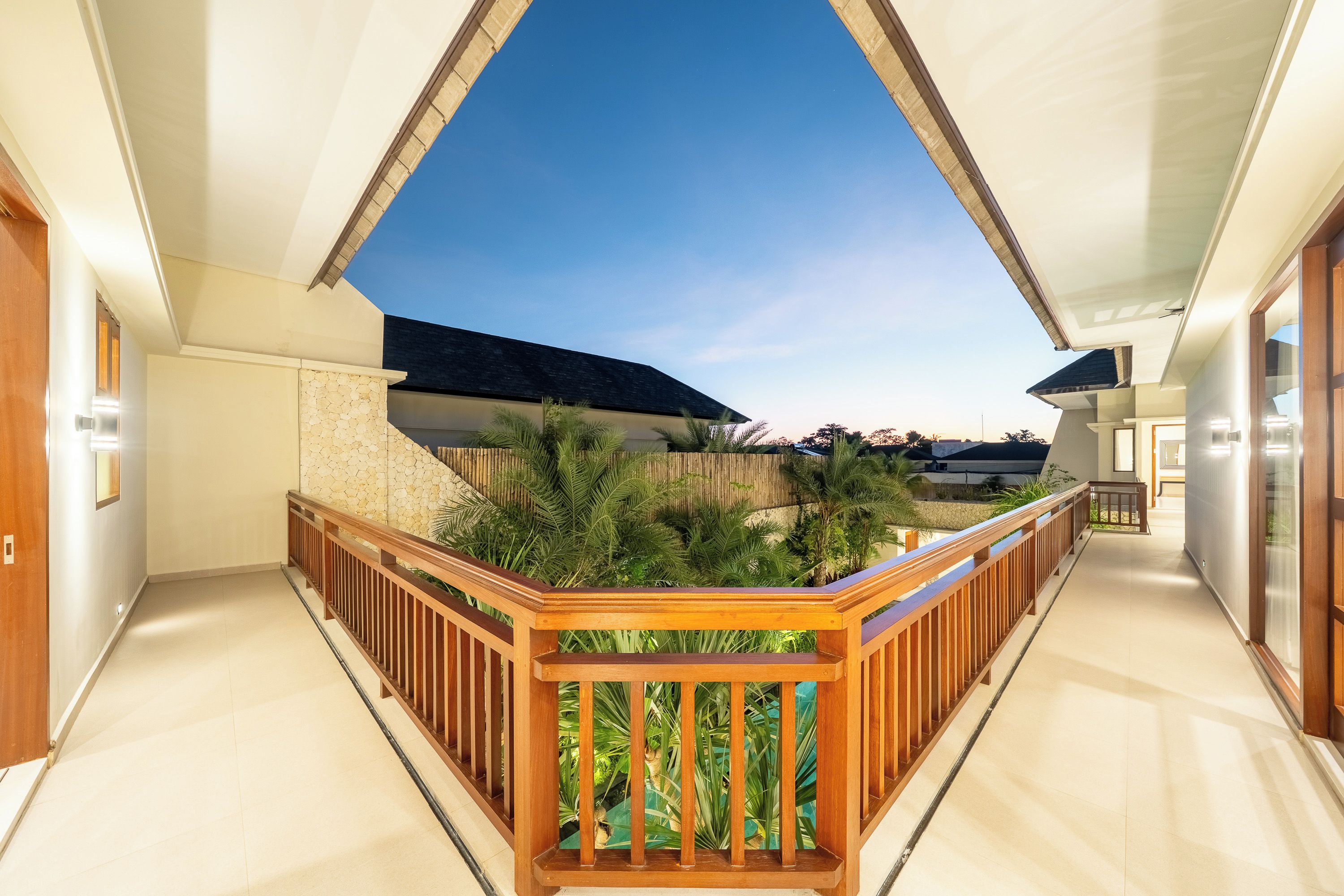 Un intérieur moderne avec une balustrade en bois, un mur en pierre et une vue sur le ciel.