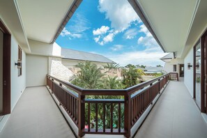 A balcony with a wooden railing, a view of a residential area, and a clear sky.