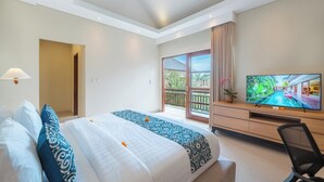 A hotel room with a large bed, a TV, a desk, and a balcony with a view of a swimming pool.