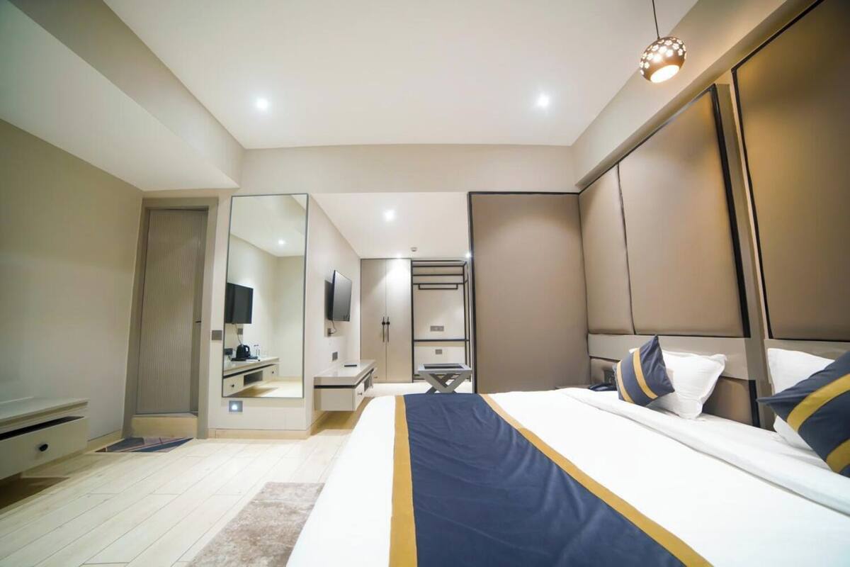 A modern bedroom with a large bed, bedside tables, a mirror, and a wardrobe.