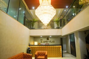 A hotel reception area with a chandelier, reception desk, and seating. - Hotel shri anand Vilas (Bhopal)